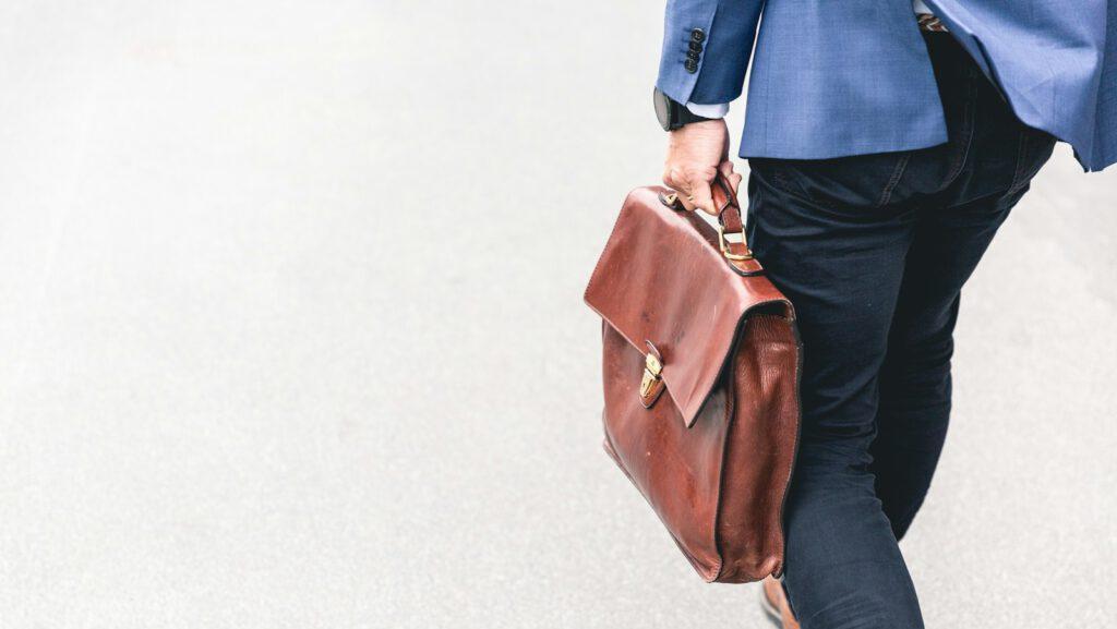 person walking holding brown leather bag